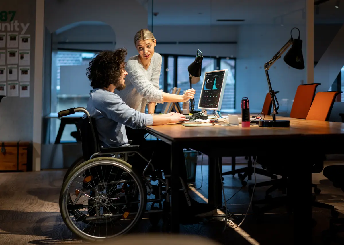 Equipo de trabajo revisando datos en un computador, con una persona en silla de ruedas